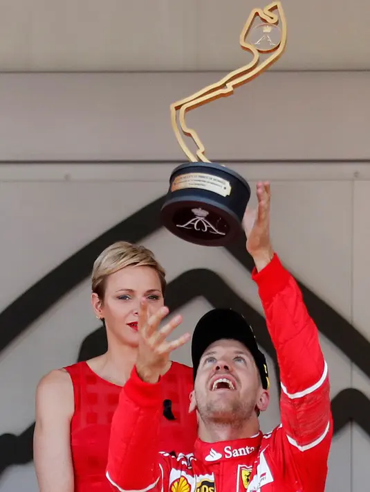 Pembalap Ferrari asal Jerman, Sebastian Vettel melempar trofi saat merayakan kemenangannya pada balapan GP Monaco di Sirkuit Monte Carlo, Minggu (28/5). Vettel finis pada urutan pertama dengan waktu satu jam 44 menit 44,340 detik (AP Photo/Claude Paris)