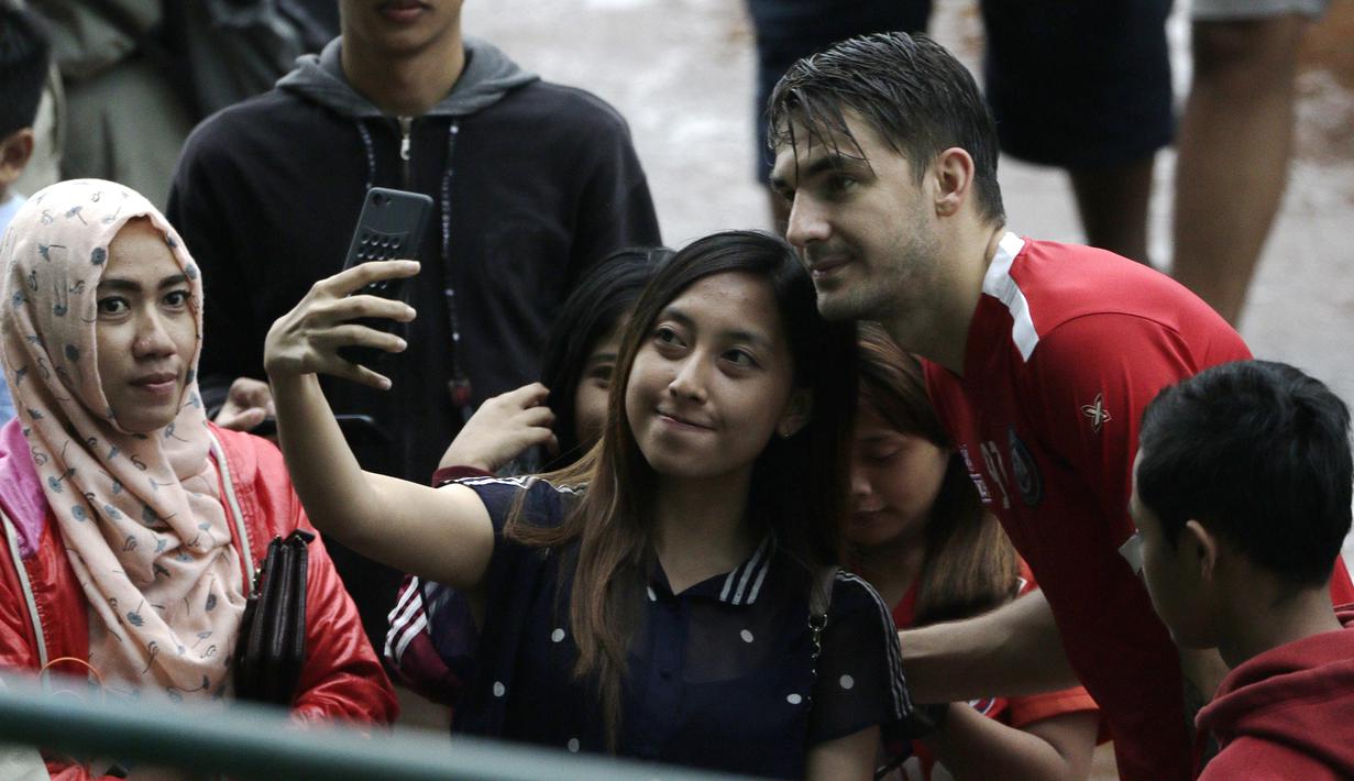 Pemain Arema FC, Pavel Smolyachenko, foto bersama dengan fans usai sesi latihan di Stadion Gajayana, Malang, Kamis (11/4). Setelah sesi latihan, pemain Arema FC melayani permintaan fans untuk foto bersama. (Bola.com/Yoppy Renato)