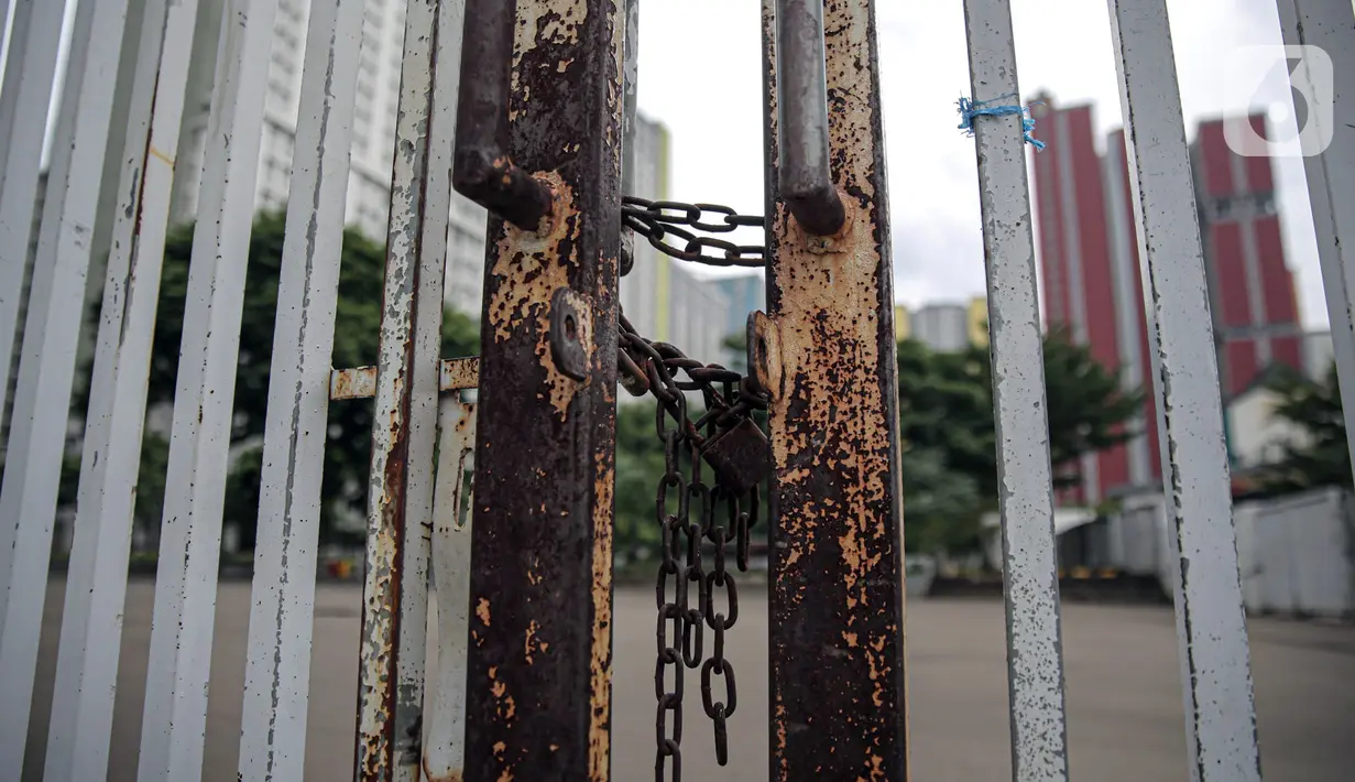 Pagar tergembok terlihat di luar Rumah Sakit Darurat COVID-19 (RSDC) Wisma Atlet, Jakarta, Minggu (25/12/2022). Pemerintah menghentikan operasional Wisma Atlet Kemayoran sebagai Rumah Sakit Darurat COVID-19 mulai akhir tahun ini seiring dengan semakin rendahnya kasus COVID-19 secara nasional dalam beberapa waktu terakhir. (Liputan6.com/Faizal Fanani)