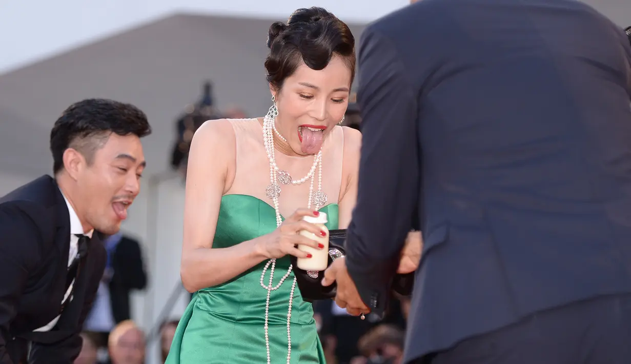 Ekspresi Aktris Korsel, Moon So-ri usai jatuh karena sepatu hak tingginya menginjak bagian bawah gaun yang panjang menjuntai di karpet merah pemutaran perdana film The Light Between Two Ocean di Venice Film Festival, Kamis (1/9). (FILIPPO MONTEFORTE/AFP)