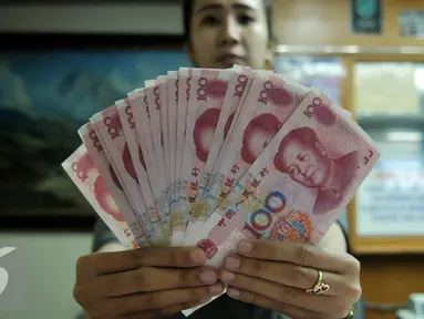 Petugas menunjukkan uang pecahan 100 Yuan di tempat penukaran uang, Jakarta, Kamis (13/8/2015). Kebijakan Tiongkok yang sengaja melemahkan (devaluasi) mata uang Yuan membuat Rupiah melemah terhadap dolar AS. (Liputan6.com/Johan Tallo)