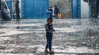 Seorang anak laki-laki berdiri di tengah hujan di sebuah sekolah yang dikelola oleh BBadan Bantuan dan Pekerjaan PBB untuk Pengungsi Palestina (UNRWA) di Rafah, Jalur Gaza selatan, Selasa (14/11/2023). (SAID KHATIB / AFP)