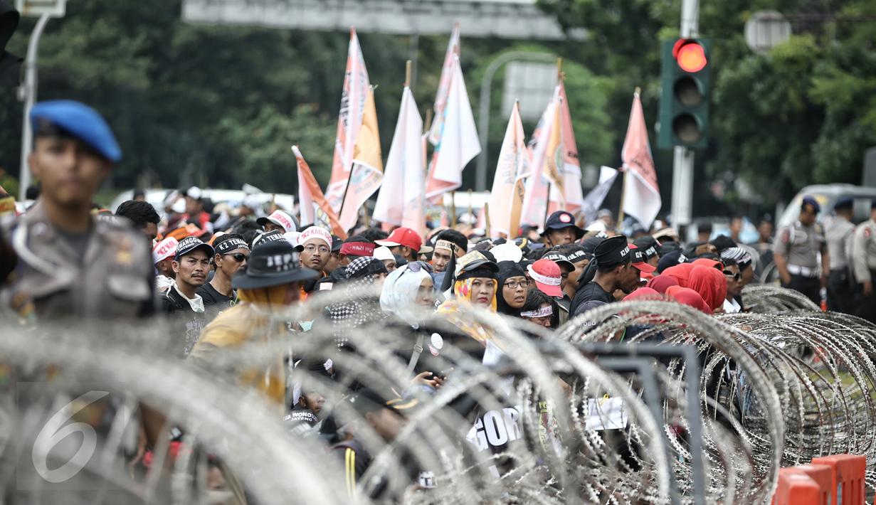 Massa berdiri di depan barikade kawat berduri yang dipasang di seputaran Istana Kepresidenan, Jakarta, Rabu (10/2). Guru honorer dari seluruh Indonesia itu menuntut Pemerintah agar mengangkat mereka sebagai PNS. (Liputan6.com/Faizal Fanani)