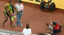 Dibantu petugas, pelari Jamaika, Usain Bolt berdiri menahan sakit usai tertabrak kameramen yang mengendarai skuter saat melakukan selebrasi kemenangan di nomor 200 meter pada Kejuaran Dunia Atletik di Beijing, Kamis (27/8). (REUTERS/Kim Kyung-Hoon)