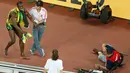 Dibantu petugas, pelari Jamaika, Usain Bolt berdiri menahan sakit usai tertabrak kameramen yang mengendarai skuter saat melakukan selebrasi kemenangan di nomor 200 meter pada Kejuaran Dunia Atletik di Beijing, Kamis (27/8). (REUTERS/Kim Kyung-Hoon)