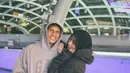 Foto mesra Adiba Khanza dan sang suami dalam outfit yang serasi. Adiba tampil sporty dengan oversized hoodie berwarna abu-abu gelap dan celana jeans, serta hijab hitam polos. Sedangkan sang suami tampil seragam mengenakan hoodie abu-abu yang lebih terang dan celana jeans. [Foto: Instagram/adiba.knza]