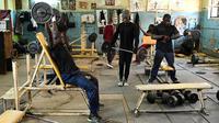 Sejumlah binaragawan mengangkat beban saat berolahraga di gym Kaloleni, di Nairobi, Kenya (9/1). (AFP Photo/Simon Maina)
