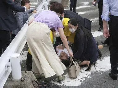 Mantan Perdana Menteri Jepang Shinzo Abe (tengah) jatuh ke tanah di Nara, Jepang barat, Jumat (8/7/2022). Abe pingsan setelah ditembak di Nara. Beberapa media melaporkan bahwa Shinzo Abe ditembak dari belakang, kemungkinan dengan senapan. (Kyodo News via AP)