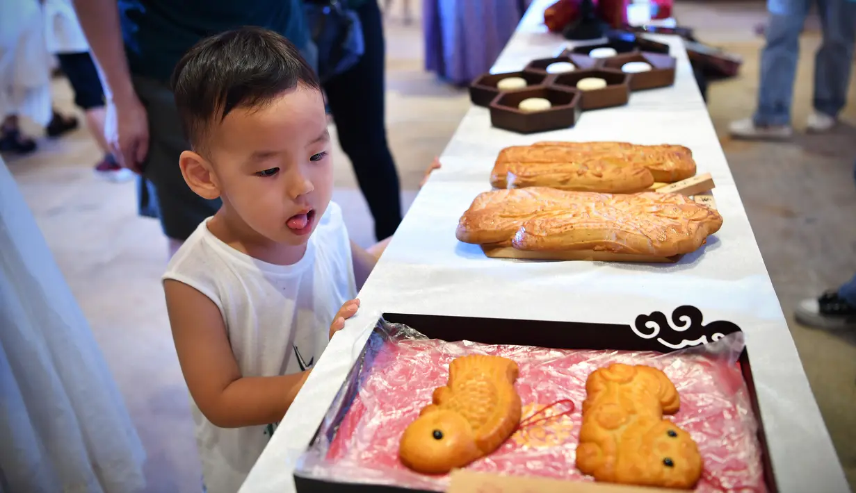 Seorang anak melihat pameran kue bulan dalam acara perayaan Festival Pertengahan Musim Gugur di Museum Hainan, Haikou, ibu kota Provinsi Hainan, China selatan (1/10/2020). (Xinhua/Guo Cheng)