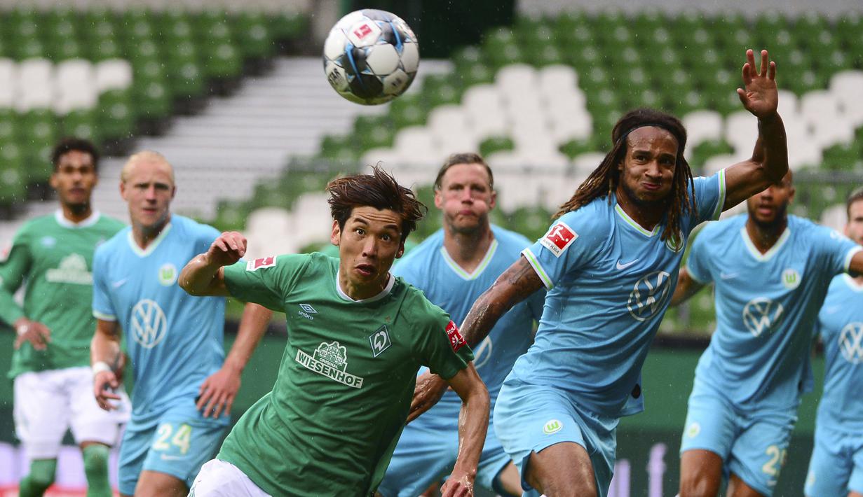 Pemain Werder Bremen, Yuya Osako, berebut bola dengan pemain Wolfsburg, Kevin Mbabu, pada laga Bundesliga di Weserstadion Minggu (7/6/2020). Werder Bremen takluk 0-1 dari Wolfsburg. (AFP/Patrik Stollarz)