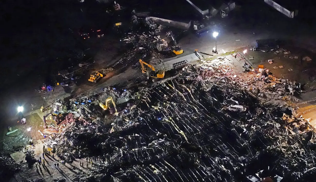 Para pekerja mencari korban selamat pada sebuah pabrik yang runtuh akibat diterjang tornado di Mayfield, Kentucky, Amerika Serikat, 11 Desember 2021. Tornado menyebabkan kerusakan signifikan di puluhan kabupaten di Kentucky. (AP Photo/Gerald Herbert)