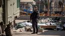 Seorang polisi Ukraina berdiri di dekat mayat yang ditutupi lembaran plastik setelah serangan roket yang digunakan untuk evakuasi sipil di sebuah stasiun kereta api di Kramatorsk, Ukraina timur (8/4/2022). (AFP/Fadel Senna)