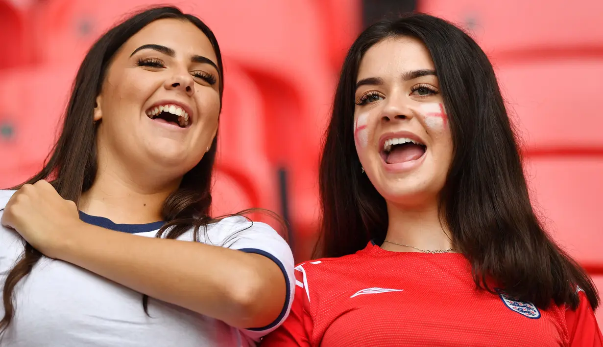 Dua suporter Timnas Inggris tersenyum melihat aksi anak asuh Gareth Southgate yang mampu menang dua gol tanpa balas atas Timnas Jerman. (Justin Tallis/Pool/AFP)