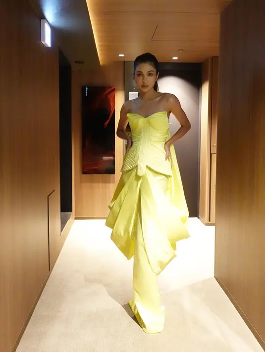 Di foto ini, Mikha mengenakan strapless dress berwarna kuning yang unik. Gaun rancangan Hian Tjen ini memiliki detail drapery yang tersambung hingga bagian belakang tubuhnya. Foto: Instagram.