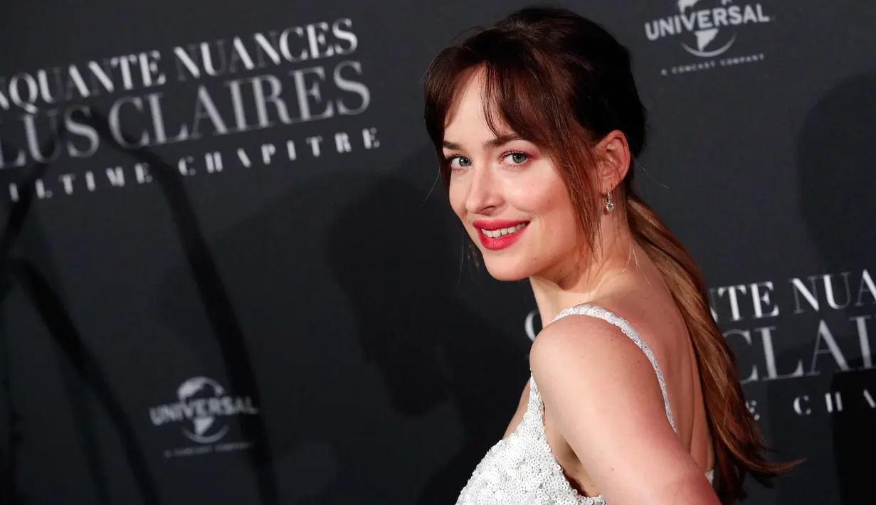 Dakota Johnson tersenyum saat menghadiri penayangan perdana film terbarunya, Fifty Shades Freed di Salle Pleyel di Paris, Prancis (6/2). Aktris 28 tahun ini tampil cantik dan seksi dengan gaun putih yang dikenakannnya. (AP Photo/Francois Mori)