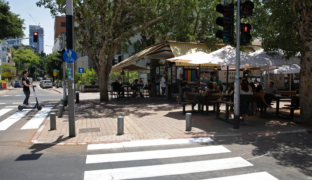 Warga Israel duduk di sebuah kedai kopi luar ruangan di Tel Aviv, Rabu (27/5/2020). Setelah lebih dari dua bulan ditutup untuk membendung penularan virus corona, restoran hingga kafe di Israel diizinkan dibuka kembali hari Rabu, 27 Mei. (AP Photo/Sebastian Scheiner)
