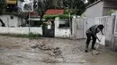 Sementara warga bekerja tanpa lelah untuk membersihkan jalan-jalan yang tersumbat setelah hujan deras. (Photo by Sakis MITROLIDIS / AFP)