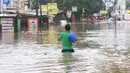 Warga melintasi banjir  yang merendam jalan Raya KH Hasyim Ashari, Ciledug ,Tangerang, Rabu (1/1/2020). Banjir setinggi dada orang dewasa membuat jalur penghubung Tangerang ke Jakarta tersebut terputus tidak dapat dilintasi. (Liputan6.com/Angga Yuniar)