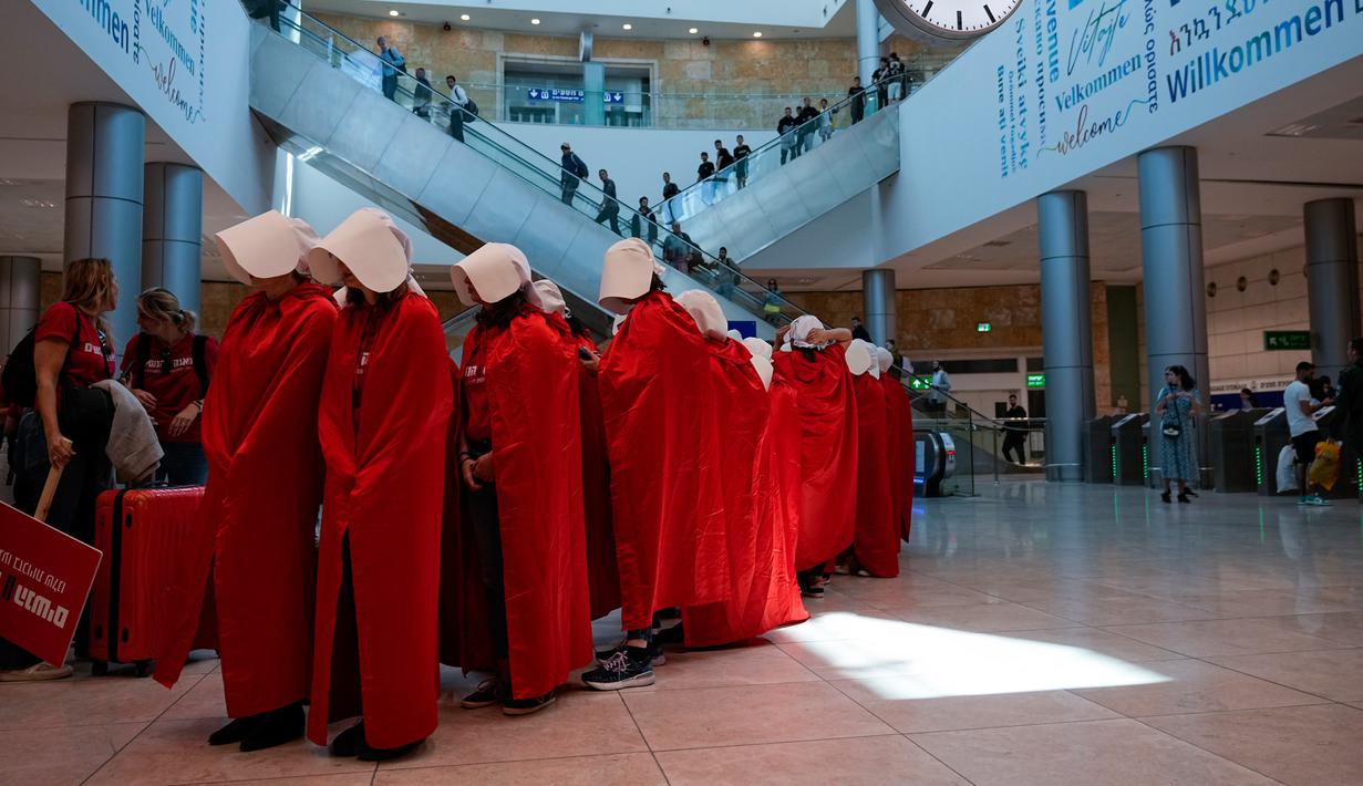 Pengunjuk rasa yang mendukung hak-hak perempuan berpakaian seperti karakter dari serial TV "The Handmaid's Tale" saat melakukan perjalanan untuk memprotes rencana pemerintah baru Perdana Menteri Benjamin Netanyahu untuk merombak sistem peradilan di sebuah stasiun kereta api di Yerusalem, Israel, 1 Maret 2023. Mengacu pada fenomena yang berkembang, harian Inggris The Guardian menggambarkan penampilan para pelayan sebagai salah satu simbol paling kuat dari protes feminis kontemporer. (AP Photo/Ohad Zwigenberg)