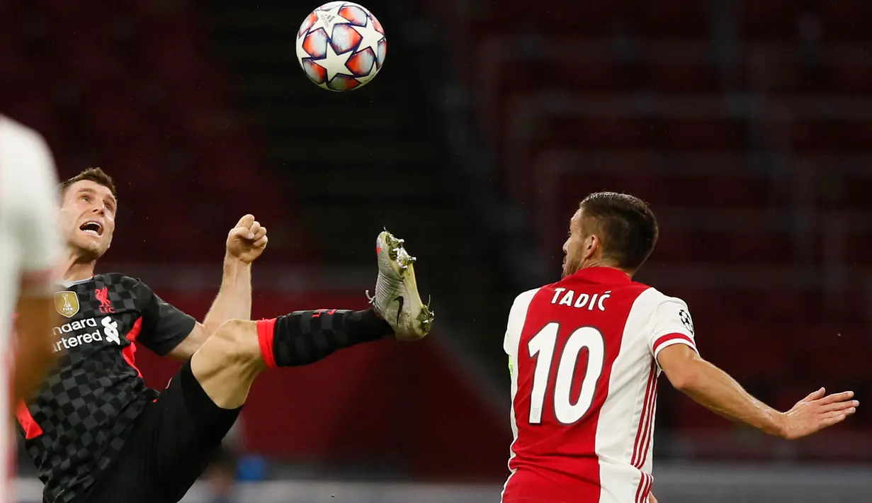 Gelandang Liverpool, James Milner berebut bola dengan pemain Ajax Amsterdam,  Dusan Tadic pada pertandingan pertama Grup D Liga Champions 2020 di Johan Cruijff Arena, Kamis (22/10/2020) dini hari WIB. Liverpool susah payah menang tipis 1-0 di kandang Ajax. (AP Photo/Peter Dejong)