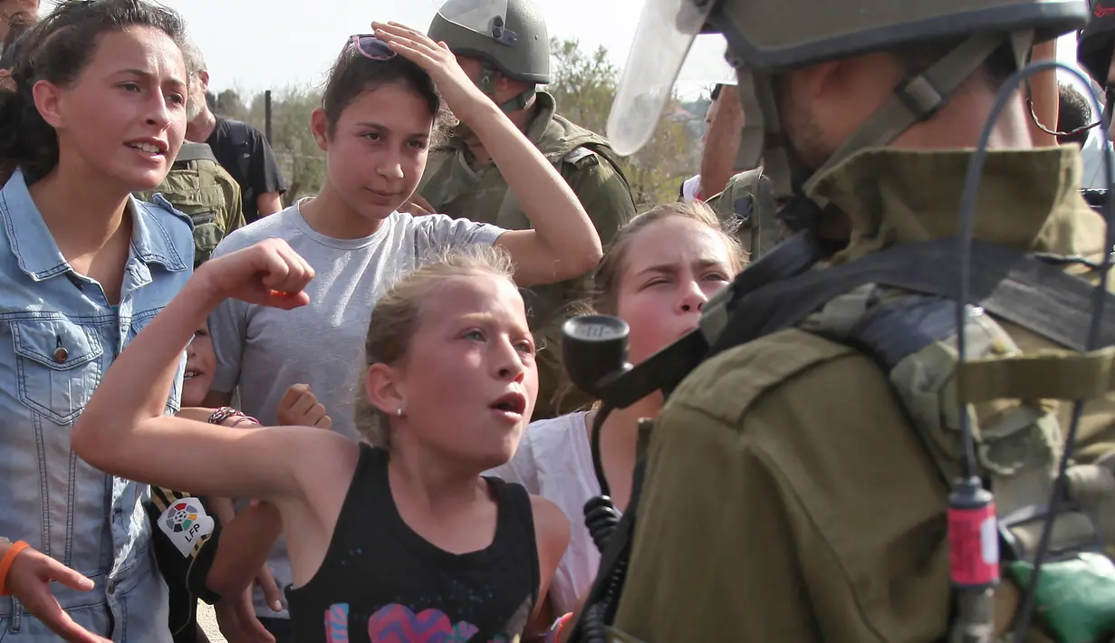 Foto yang diambil pada 2 November 2012 menunjukkan Gadis Palestina, Ahed Tamimi mengepalkan tangannya didepan tentara Israel saat melakukan demonstrasi menentang penyitaan tanah warga Palestina oleh Israel di Desa Nabi Saleh. (AFP Photo/Abbas Momani)