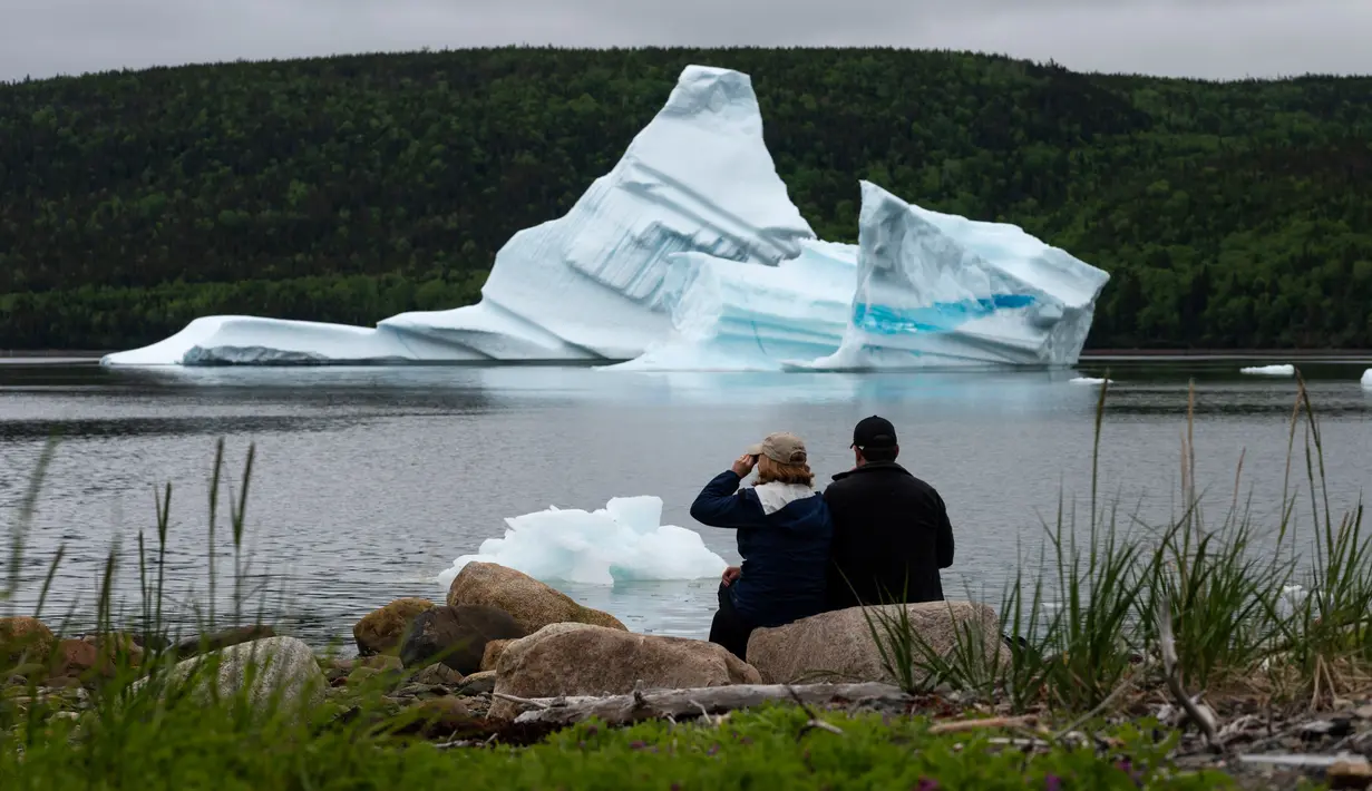Wisatawan menyaksikan pemandangan gunung es terapung dekat King's Point, Newfoundland, Kanada, 3 Juli 2019. Gunung es terapung memberi pemandangan kontras yang unik, terutama bagi penggemar fotografi. (Johannes Eisele/AFP)