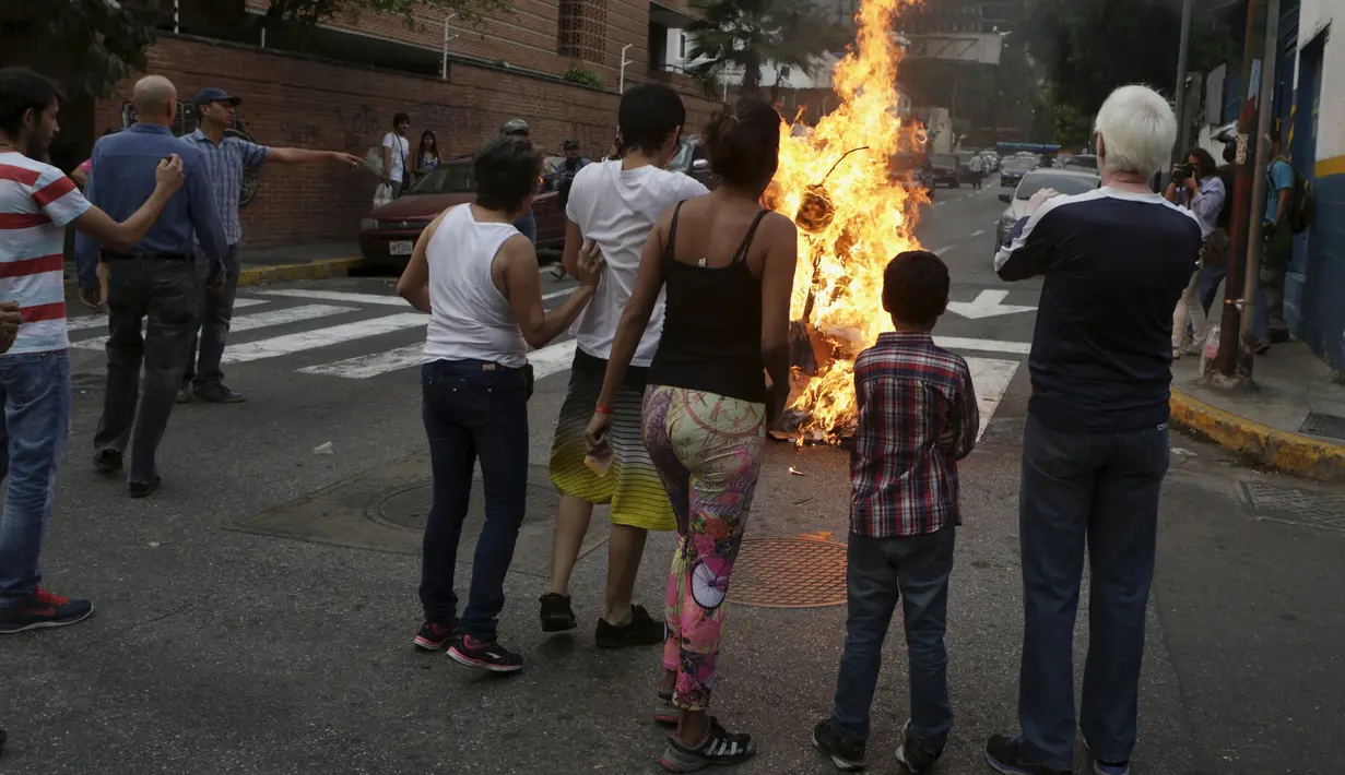 Patung yang dipasang gambar Presiden Venezuela Nicolas Maduro dibakar oleh warga di Caracas , Venezuela, (27/3). Hal ini dilakukan dalam perayaan Paskah di Caracas. (REUTERS / Marco Bello)