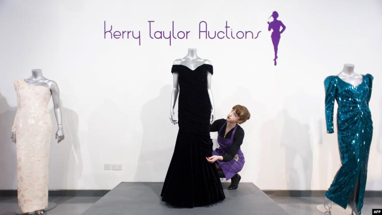 Seorang staf di balai lelang Kerry Taylor Auction di London, 15 Maret 2013, berpose dengan gaun malam Victor Edelstein (tengah) yang digunakan Putri Diana dalam acara jamuan makan malam kenegaraan di Gedung Putih pada 1985.