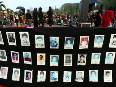 Aktivis menunjukkan foto para korban HAM saat aksi Kamisan ke-502 di seberang Istana Merdeka, Jakarta, Kamis (10/8). Aksi meminta pemerintah mewujudkan komitmen dalam menyelesaikan kasus pelanggaran HAM berat pada masa lalu. (Liputan6.com/Johan Tallo)