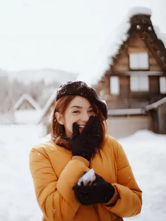 Perempuan berumur 27 tahun ini tampak menikmati liburannya ke Jepang. Di tengah salju Jepang, ia menggunakan Jaket tebal berwarna kuning lengkap dengan sarung tangan dan topi hitam. Senyumannya di tengah salju sangat memesona.  (Liputan6.com/IG/@enzystoria)