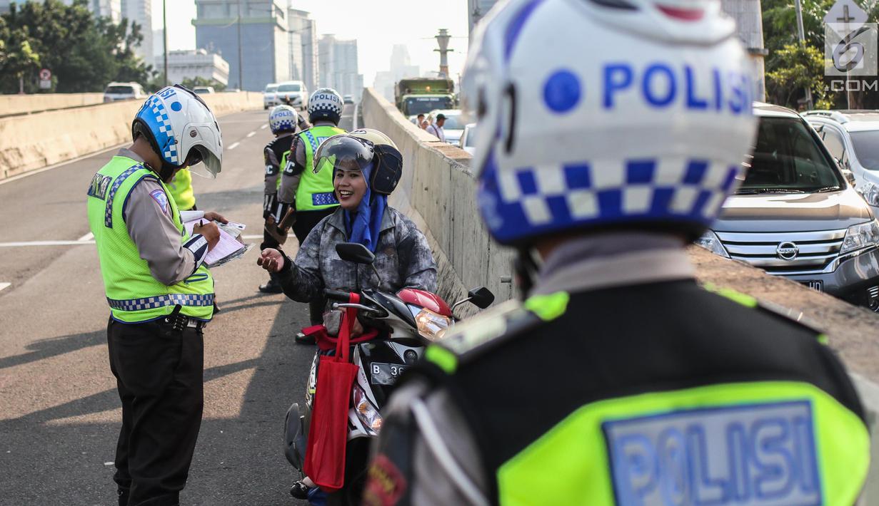 Petugas kepolisian memberikan surat tilang kepada pengendara sepeda motor  yang melintasi JLNT Kampung Melayu-Tanah Abang, Jakarta, Selasa (25/7). Sepeda motor dilarang melintas di JLNT tersebut karena merupakan jalur cepat. (Liputan6.com/Faizal Fanani)