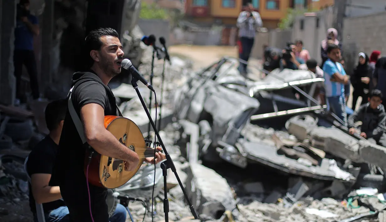 Penampilan seorang penyanyi Palestina selama acara musik di puing-puing bangunan yang baru-baru ini hancur oleh serangan udara Israel di kota Gaza, Selasa (14/5/2019). Aksi itu untuk menyerukan pemboikotan terhadap Kontes Lagu Eurovision 2019 yang diselenggarakan di Israel. (REUTERS/Mohammed Salem)