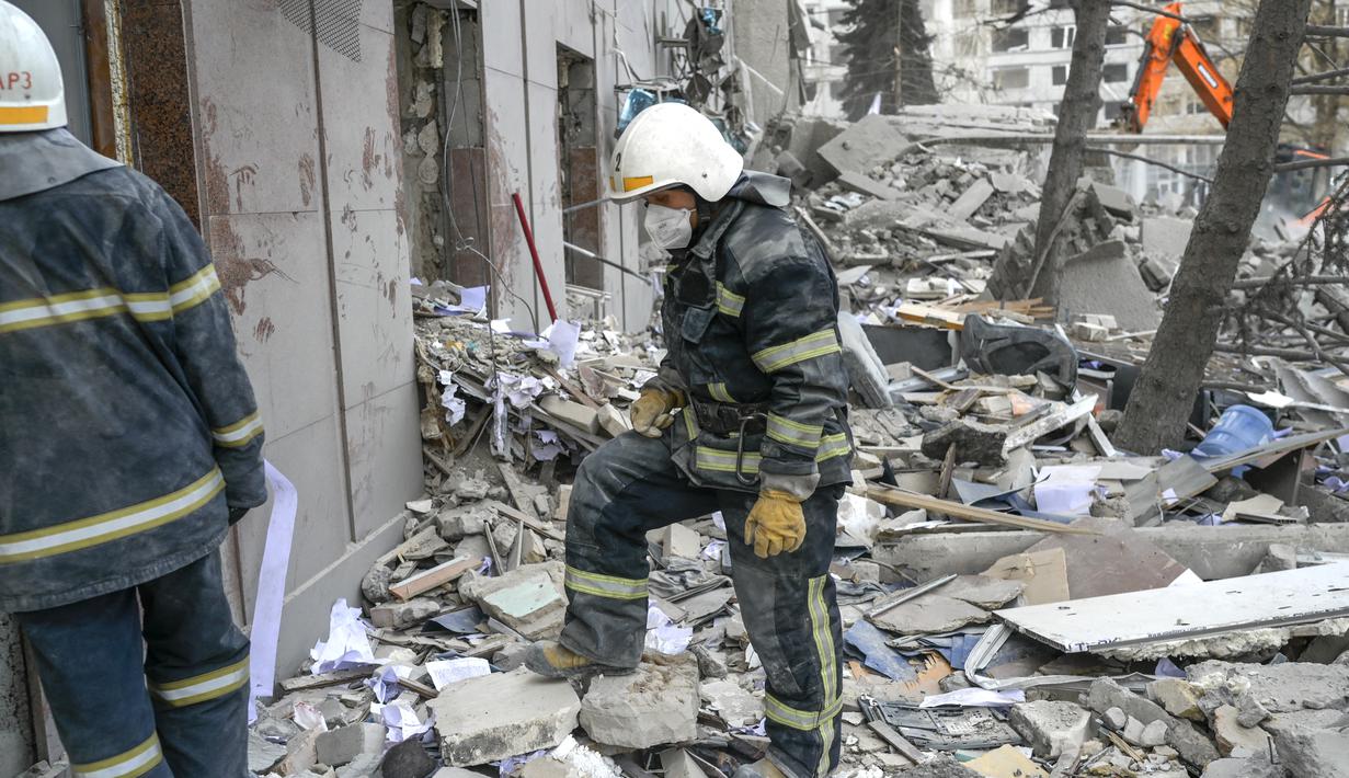 Petugas pemadam kebakaran membersihkan puing-puing gedung pemerintah yang terkena roket Rusia di Mykolaiv (29/3/2022). Gubernur Vitaly Kim mengatakan bahwa kebanyakan orang di dalam gedung tidak terluka tetapi beberapa warga sipil dan tentara belum ditemukan. (AFP/Bulent Kilic)