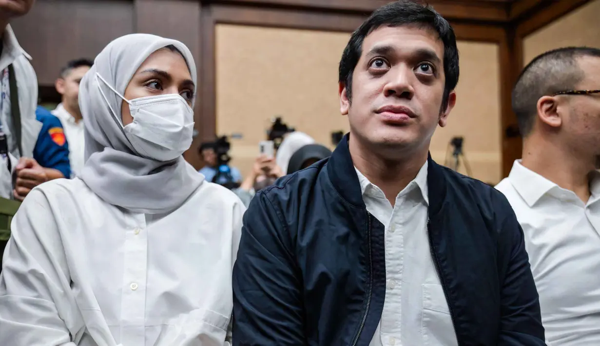 Dalam putusan yang dibacakan pada Jumat 27 Februari dini hari WIB, majelis Hakim menyatakan Muhammad Kerry Adrianto Riza terbukti bersalah dalam perkara korupsi tata kelola minyak mentah dan produk kilang pada PT Pertamina Subholding, dan Kontraktor Kontrak Kerja Sama periode 2018-2023. Tampak dalam foto, mantan Wakil Direktur Optimalisasi Produk di PT Kilang Pertamina Internasional, Muhammad Kerry Adrianto Riza (kanan), yang juga putra pengusaha Riza Chalid, didampingi istrinya Atya Sardadi (kiri), sesaat sebelum mengikuti sidang pembacaan vonis di Pengadilan Tindak Pidana Korupsi, Jakarta, Kamis 26 Februari 2026. (BAY ISMOYO/AFP)