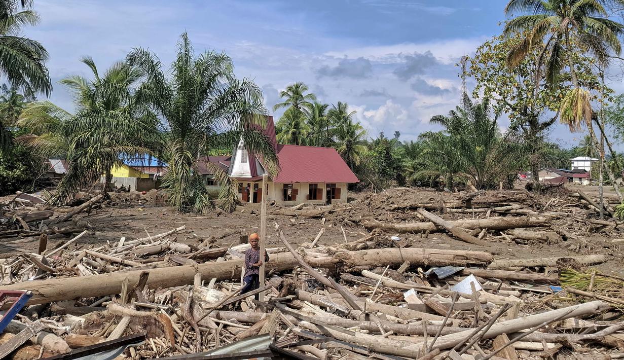 Di tengah duka mendalam akibat banjir bandang dan tanah longsor yang melanda wilayah mereka, umat Protestan tetap menunjukkan keteguhan iman dengan melaksanakan ibadah Natal. Tampak dalam foto, Gereja Protestan Angkola (tengah latar belakang) terlihat di tengah kehancuran akibat banjir di desa Aek Ngadol, Tapanuli Selatan, Sumatera Utara, pada Kamis 25 Desember 2025, setelah banjir dan tanah longsor yang melanda di daerah tersebut pada akhir November 2025 lalu. (AMROE/AFP)
