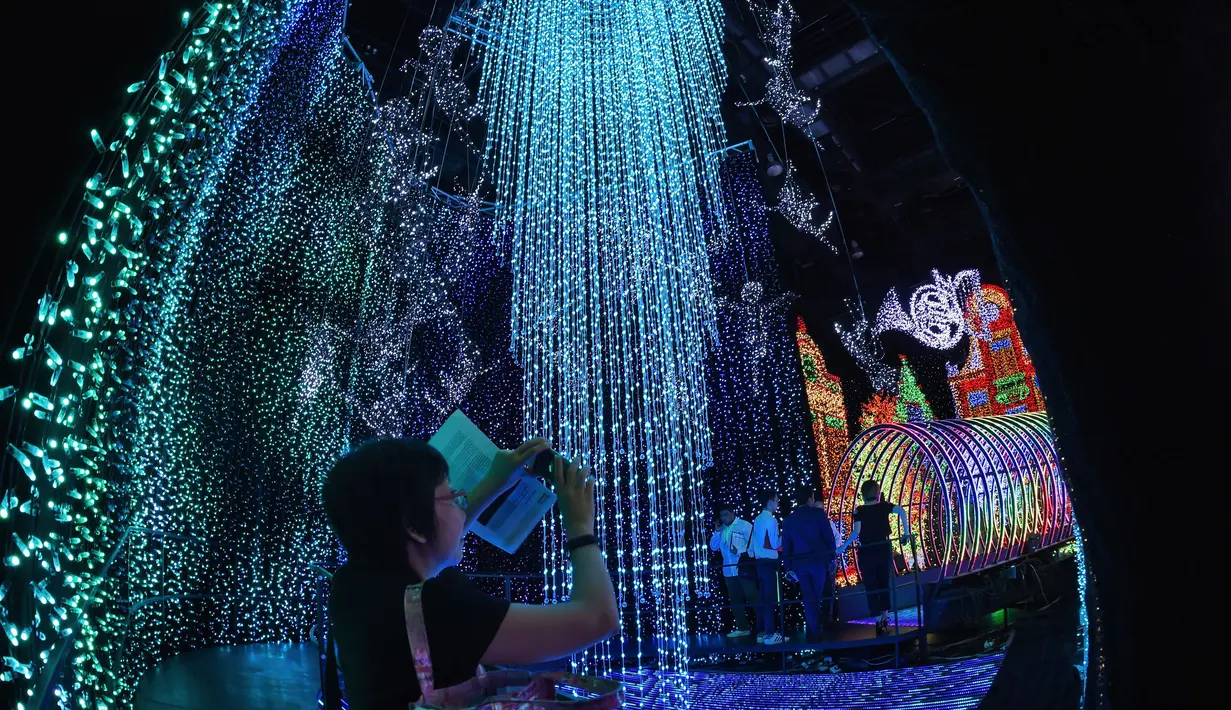 Seorang pengunjung memotret hiasan lampu-lampu Natal di taman hiburan Universal Studio Singapura, Kamis (17/11). Taman hiburan ini memecahkan rekor Guinness dengan hiasan lampu Natal sebanyak 824.961 buah. (AFP PHOTO/ Roslan Rahman)