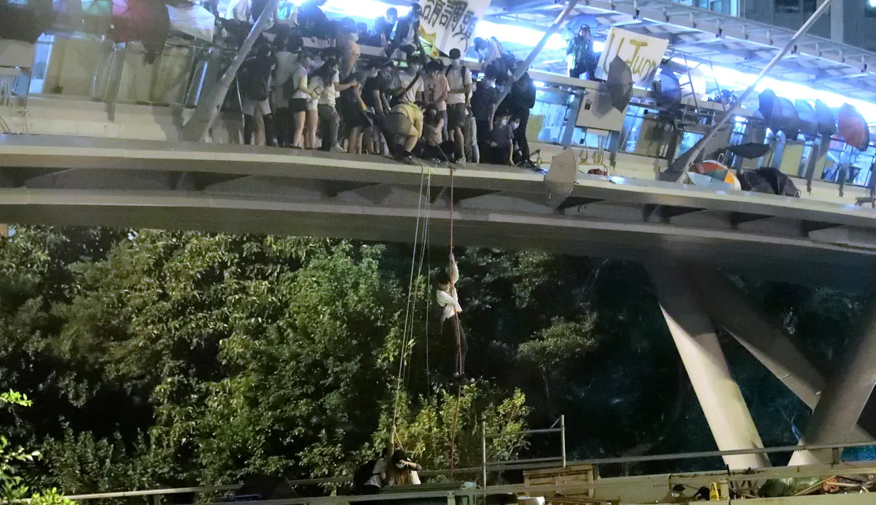 Demonstran menuruni jembatan menggunakan tali untuk melarikan diri dari Universitas Politeknik Hong Kong di Distrik Hung Hom, Hong Kong, Senin (18/11/2019). Lusinan demonstran melarikan diri dari Universitas Politeknik Hong Kong yang dikepung polisi selama berhari-hari. (AP Photo/Kin Cheung)