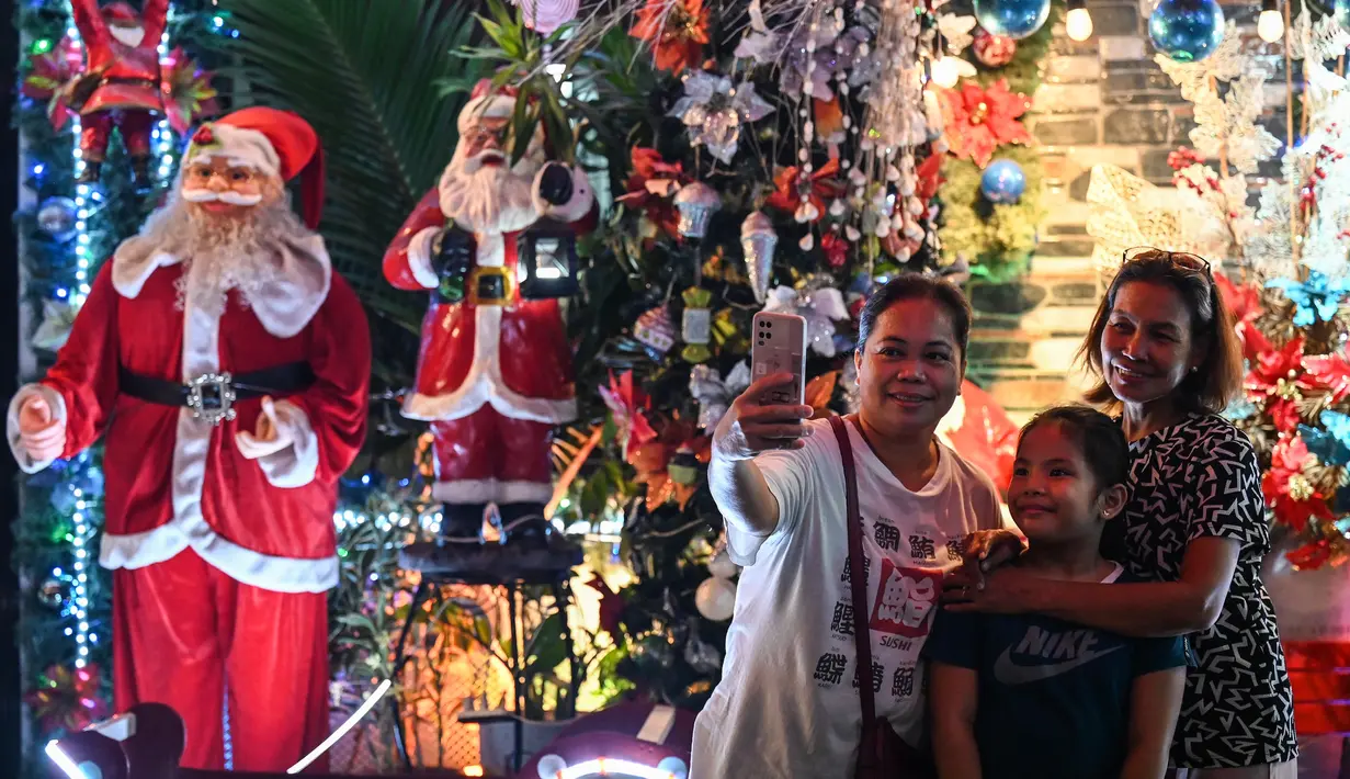 Orang-orang berfoto di depan sebuah rumah bertema Natal di Manila (21/12/2022). Perayaan Natal tinggal menghitung hari, warga Manila antusias mengunjungi rumah yang didekor dengan ornamen dan hiasan Natal itu. (AFP/Jam Sta Rosa)