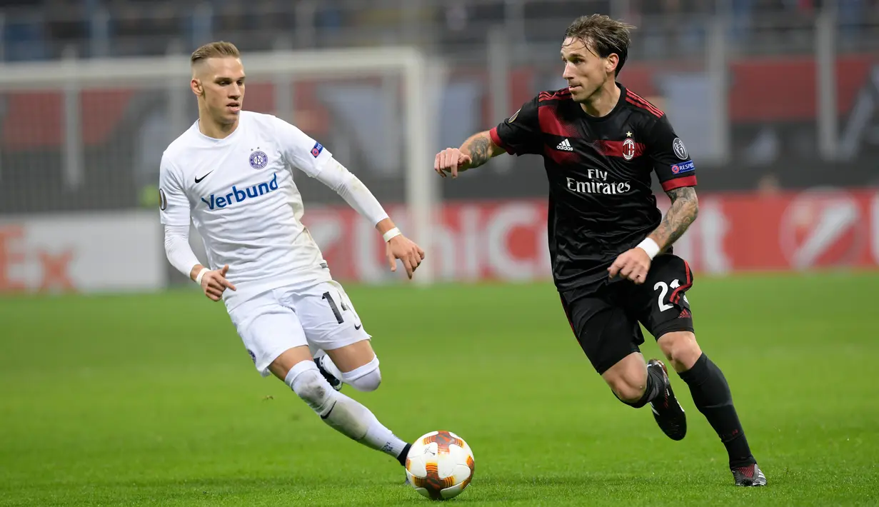Gelandang AC Milan, Lucas Biglia berebut bola pemain Austria Wien, Christoph Monschein pada matchday kelima Liga Europa di Stadion San Siro, Jumat (24/11). AC Milan memastikan diri lolos sebagai juara Grup D usai menang 5-1. (MIGUEL MEDINA / AFP)