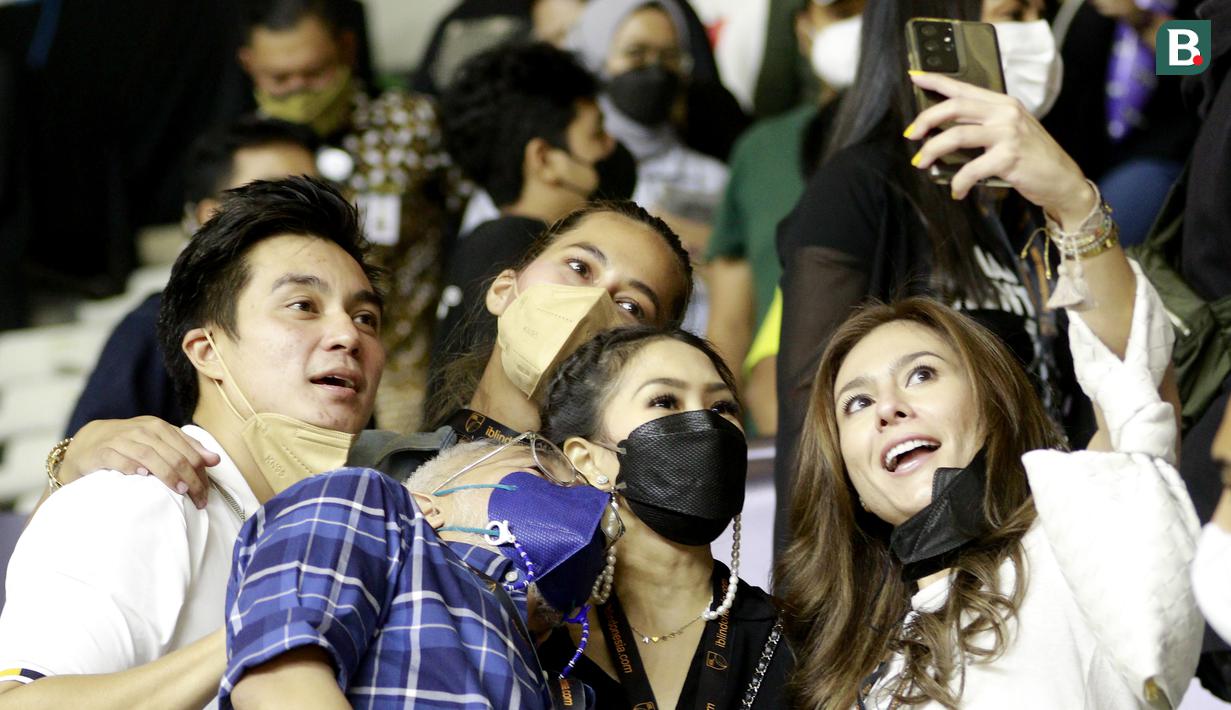 Artis Wulan Guritno, Baim Wong, Paula Verhoeven Lukman Sardi, melakukan swafoto saat menonton pertandingan Pelita Jaya melawan West Bandits Solo pada laga IBL 2022 di Hall Basket GBK, Jakarta, Jumat (21/01/2022). (Bola.com/M Iqbal Ichsan)