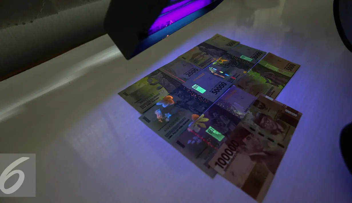 Gambar uang kertas rupiah disinari lampu ultraviolet di kantor Peruri, Karawang, Jawa Barat, Rabu (18/1). Rupiah memiliki sistem pengamanan tiga level dan menjadi mata uang yang pengamanannya sangat kompleks. (Liputan6.com/Faizal Fanani)