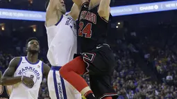 Pemain Chicago Bulls, Lauri Markkanen (kanan) melakukan tembakan melewati adangan pemain  Warriors, Zaza Pachulia pada laga NBA basketball game di Oracle Arena, Oakland, (24/11/2017). Warriors menang 143-94. (AP/Jeff Chiu)