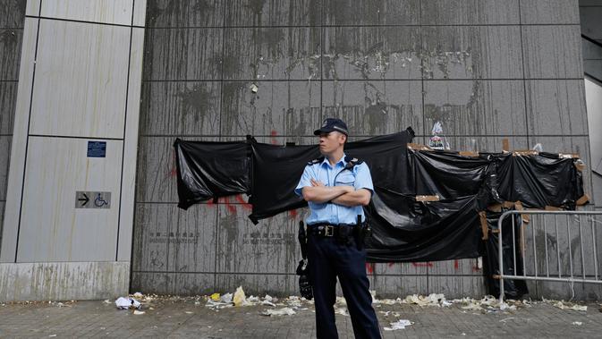 Polisi berjaga di pintu masuk utama kantor polisi yang dirusak di Hong Kong, Sabtu (22/6/2019). Markas polisi tersebut digeruduk ribuan demonstran yang menuntut pembebasan massa yang ditangkap dalam aksi menolak RUU Ekstradisi. (AP Photo/Vincent Yu)