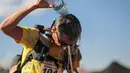 Seorang peserta mendinginkan kepalanya dengan menyiramkan air saat mengikuti kompetisi Marathon des Sables ke-33 di gurun Sahara, Maroko (11/4). (AP Photo / Mosa'ab Elshamy)