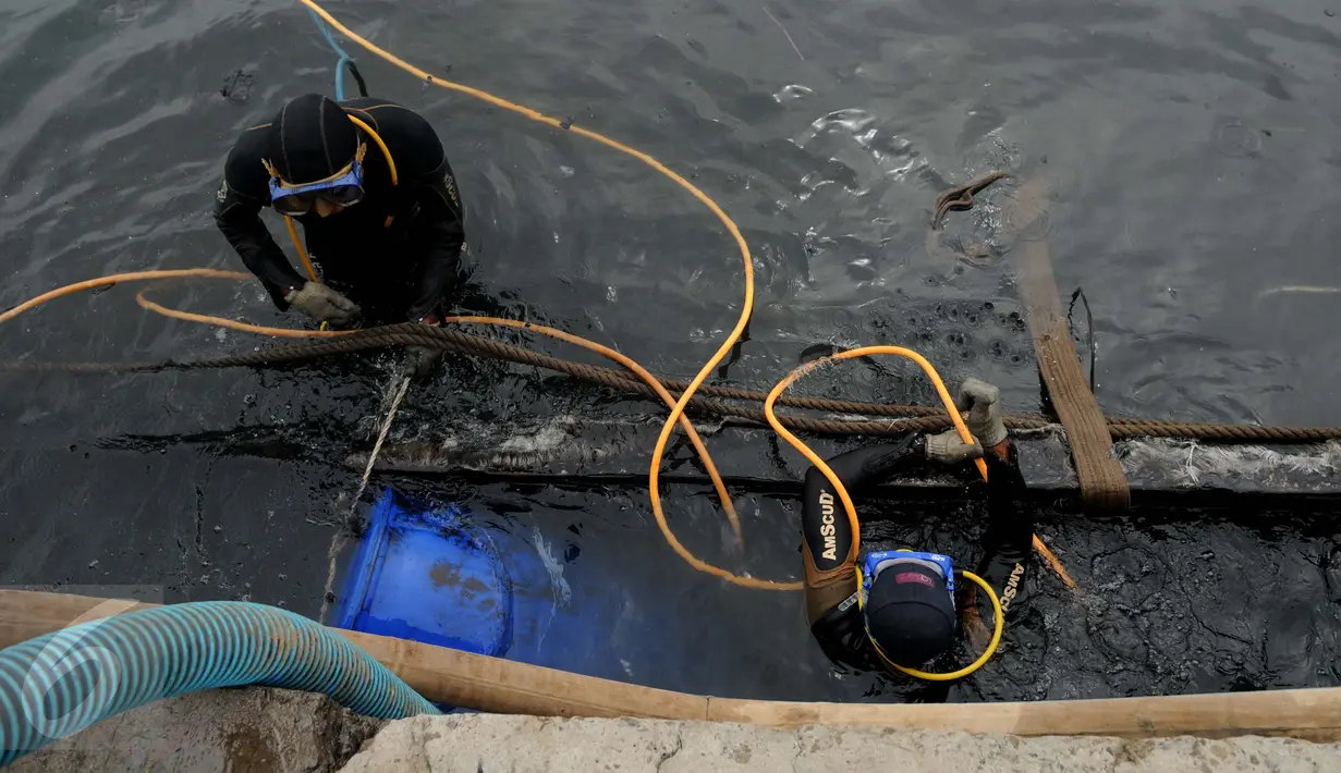 Petugas Basarnas dan Pol air memasang drum kosong ke sekeliling bangkai kapal Zahro Express di Pelabuhan Muara Angke, Jakarta, Rabu (4/1). Bangkai kapal Zahro Express mulai diangkat untuk mempermudah penyelidikan KNKT. (Liputan6.com/Gempur M Surya)
