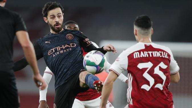 Gelandang Manchester City, Bernardo Silva mencoba menendang bola melewati penyerang Arsenal, Gabriel Martinelli pada perempatfinal Piala Liga Inggris di Emirates Stadium, Rabu (23/12/2020) dini hari WIB. Man City ke semifinal Piala Liga Inggris lewat skor 4-1 atas Arsenal. (AP Photo/Frank Augstein)
