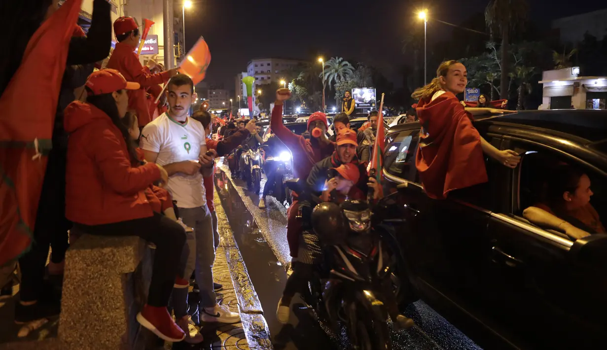 Suporter Maroko merayakan setelah pertandingan perempat final Piala Dunia kontra Portugal di jalan-jalan di Casablanca, Maroko, Sabtu (10/12/2022). Maroko mengubur mimpi Cristiano Ronaldo lewat gol semata wayang yang diciptakan Youssef En-Nesyri di babak pertama. (AP Photo/Abdeljalil Bounhar)