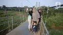 Warga asyik berswafoto bersama keluarga di atas jembatan gantung, Kelurahan Curug, Bojongsari, Kota Depok, Jawa Barat, Senin (24/8/2020). Setiap sore, warga sekitar bermain di jembatan tersebut sambil menikmati matahari tenggelam. (merdeka.com/Dwi Narwoko)