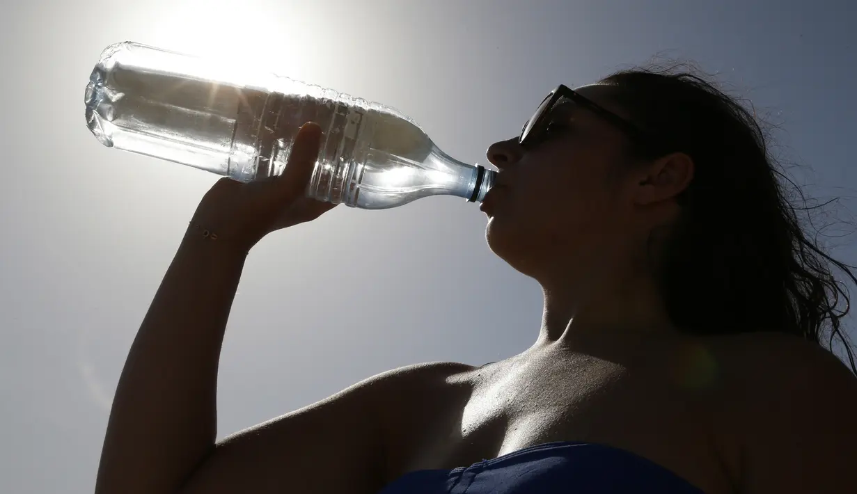 Seorang wanita minum air di pantai Ricanto di Ajaccio, di pulau Corsica, Mediterania Prancis, (1/8). Suhu udara di Corsica telah mencapai 40 C (104 F). Akibat suhu yang panas, warga Prancis mengabiskan waktunya dipantai. (AFP Photo/Pascal Pochard Casabian