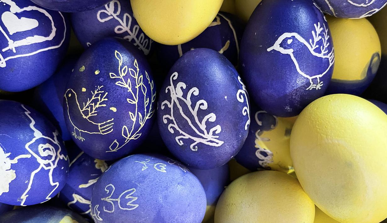 Telur Paskah yang dihias oleh wanita dan anak-anak Ukraina untuk tentara terlihat di restoran Georgia di Lviv, Ukraina, 20 April 2022. Lebih dari selusin wanita dan anak-anak menghias telur rebus dan es roti Paskah tradisional dengan warna kuning dan biru, warna bendera Ukraina. (Alice HACKMAN/AFP)
